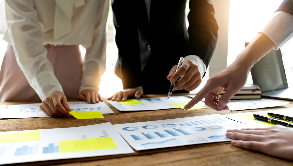 three people working at a table on reports with charts