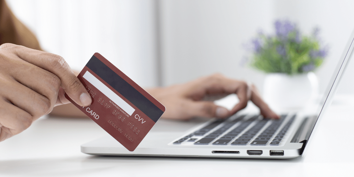 Hand paying with a credit card on a laptop Hand paying with a credit card on a laptop