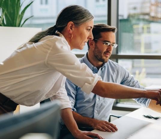 two coworkers in an office at a desk working on a project